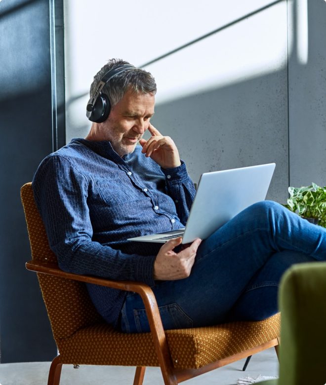 Man using headphones and laptop at home in North Carolina.