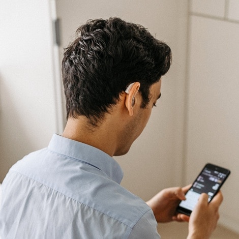 young man looking at phone with hearing aids